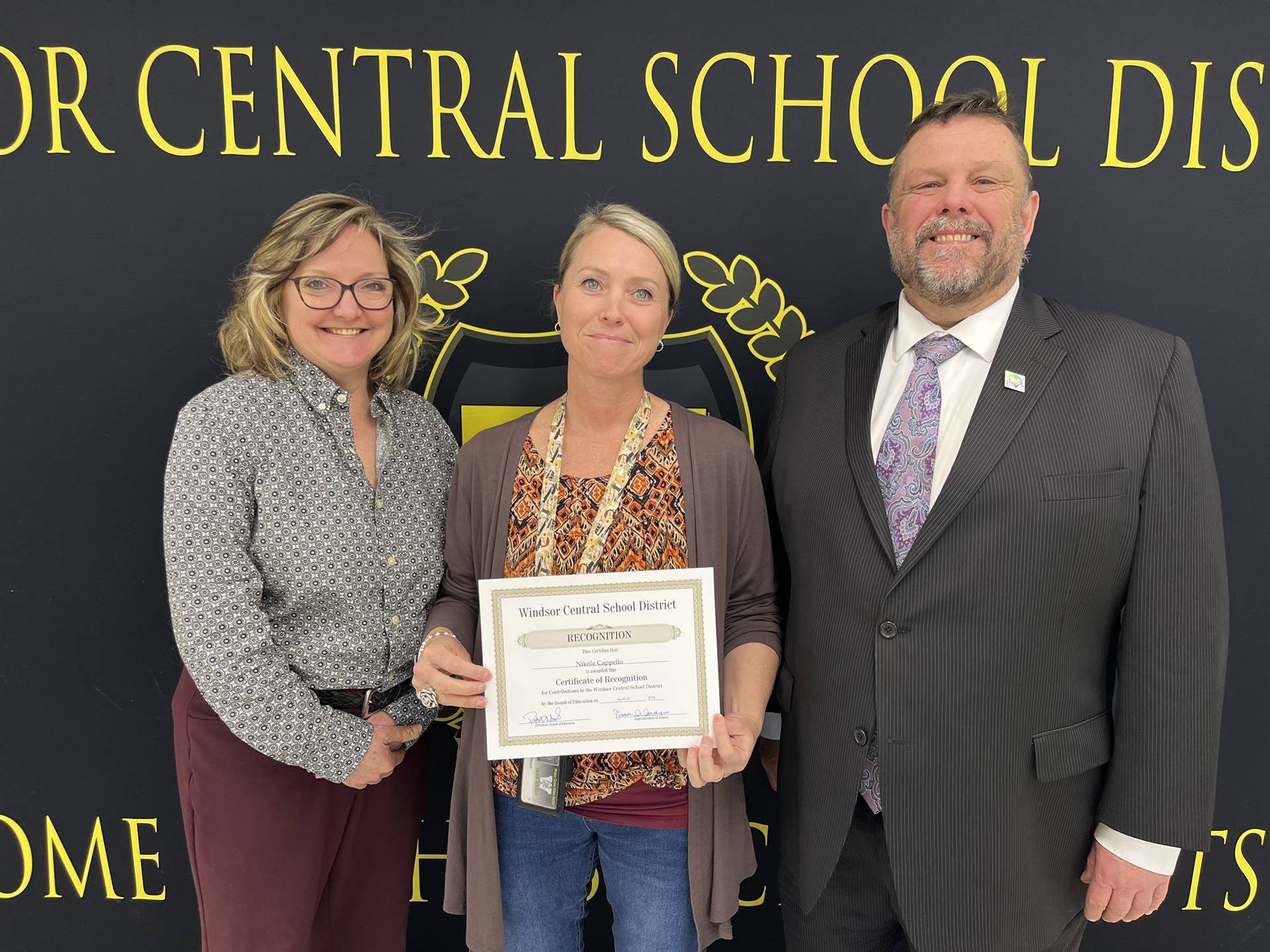Margo Kibbler, Nikole Cappello, and Pete Nowacki standing in front of a banner