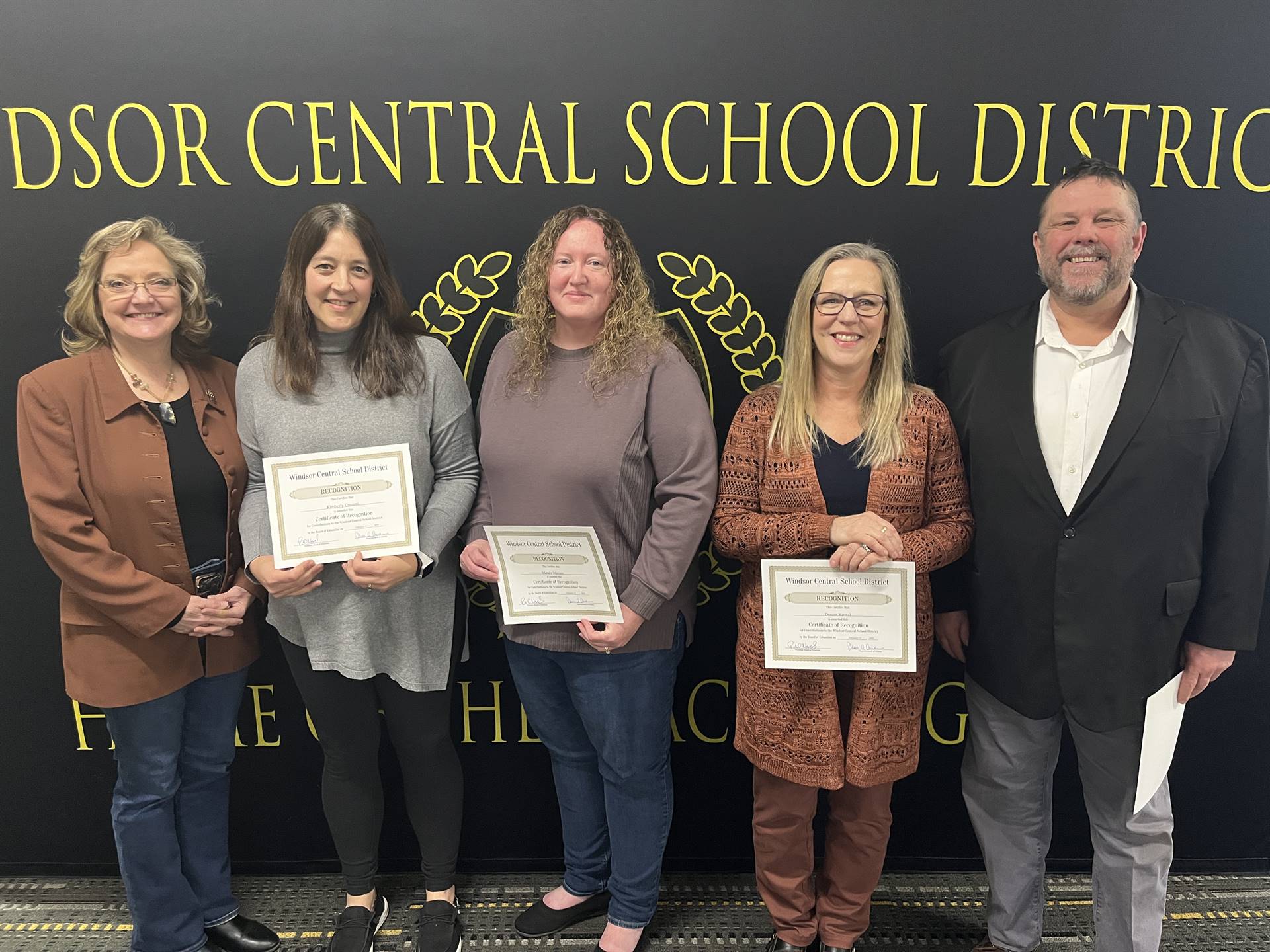 Four women and a man standing in front of a backdrop