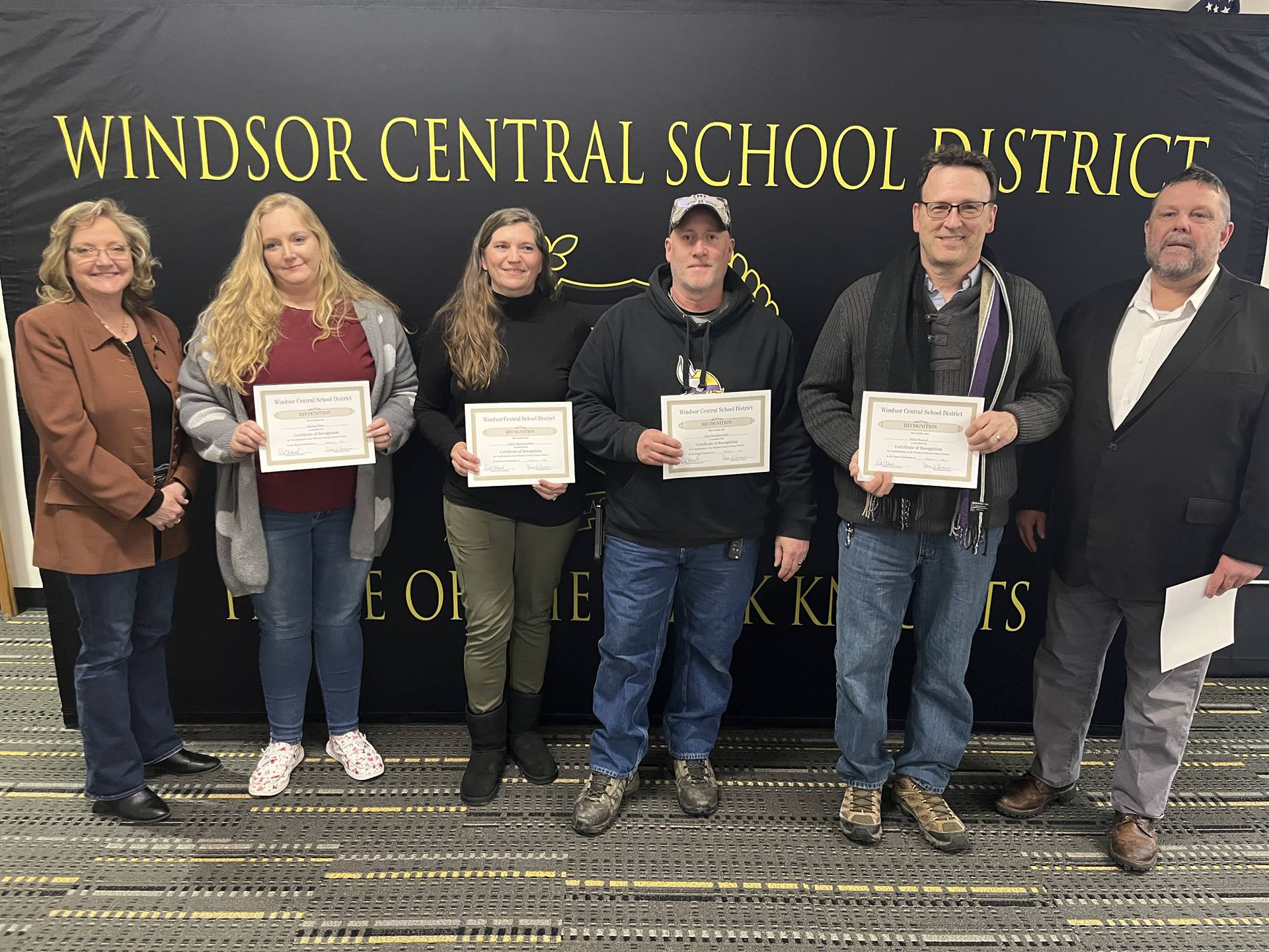 Three women and three men standing in front of a backdrop