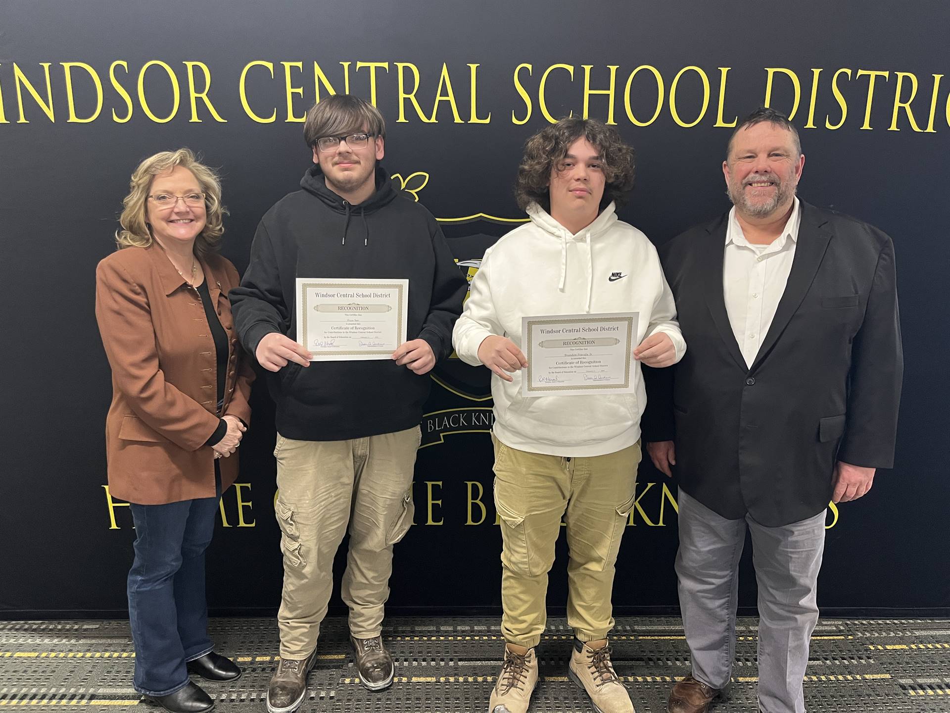 A woman and three men standing in front of a backdrop