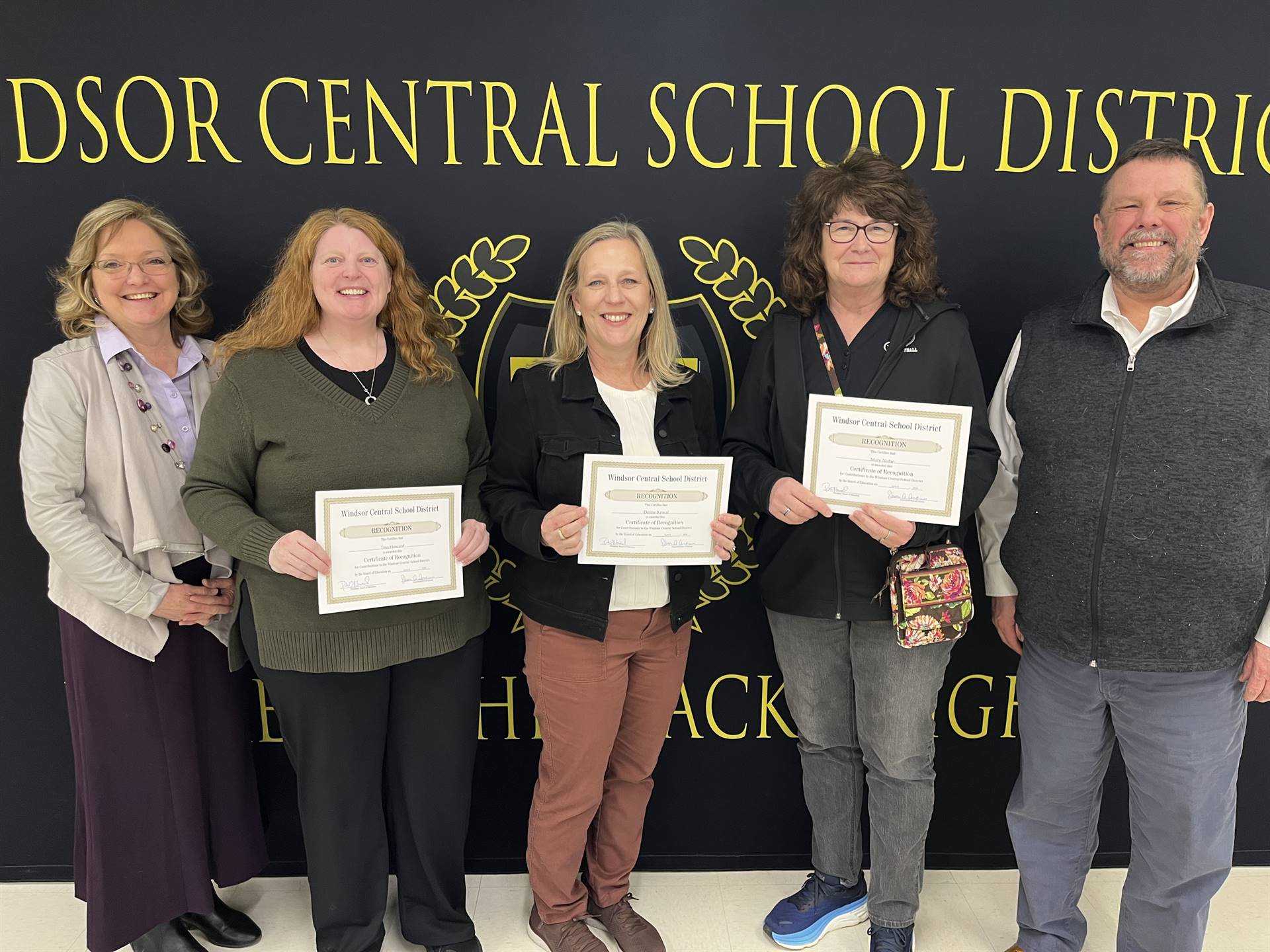 Four women and a man standing in front of a banner