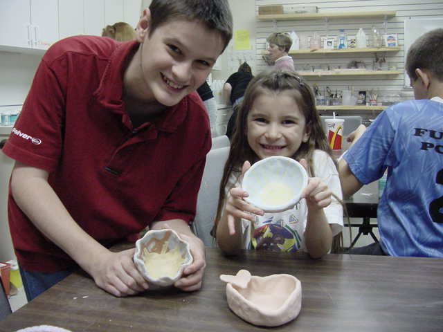 Kids holding bowls they made