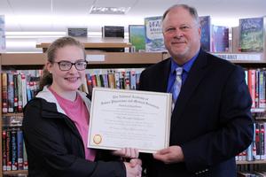 A female student receives a certificate from her principal