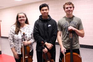 A girl and boy holding violins and a boy with a cello