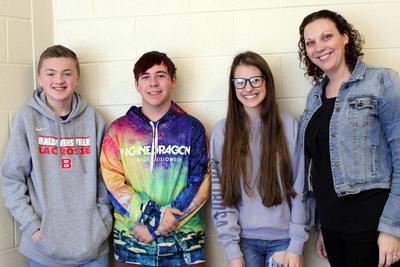 Two male students and a female student standing with a female teacher