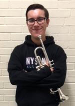 a boy holding a trumpet stands in front of a brick wall 