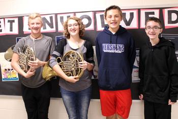 A boy and a girl hold a French horn and two boys stand next to them