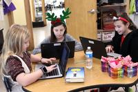 Three young girls type on their laptops