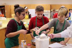 a girl and two boys measure flour into a cup 