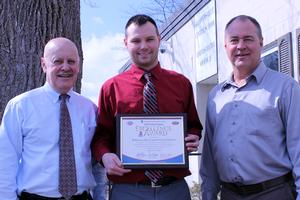 three men holding a plaque