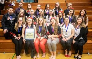 a group of girls wearing medals sit on bleachers