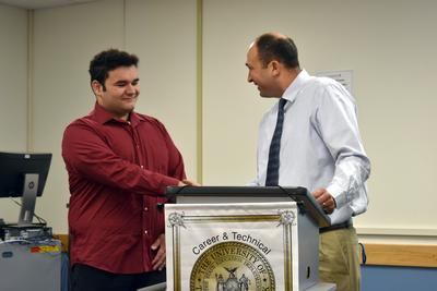 a teenage boy and a man shake hands