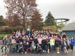 a large group of students stand in front of a roller coaster