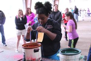 a girl dips string into wax to make a candle