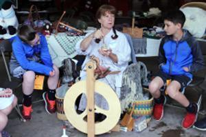 a woman demonstrates how to spin thread