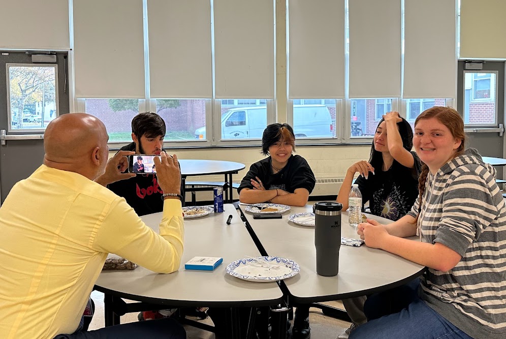 image of superintendent shooting video with 4 students at a cafeteria table 