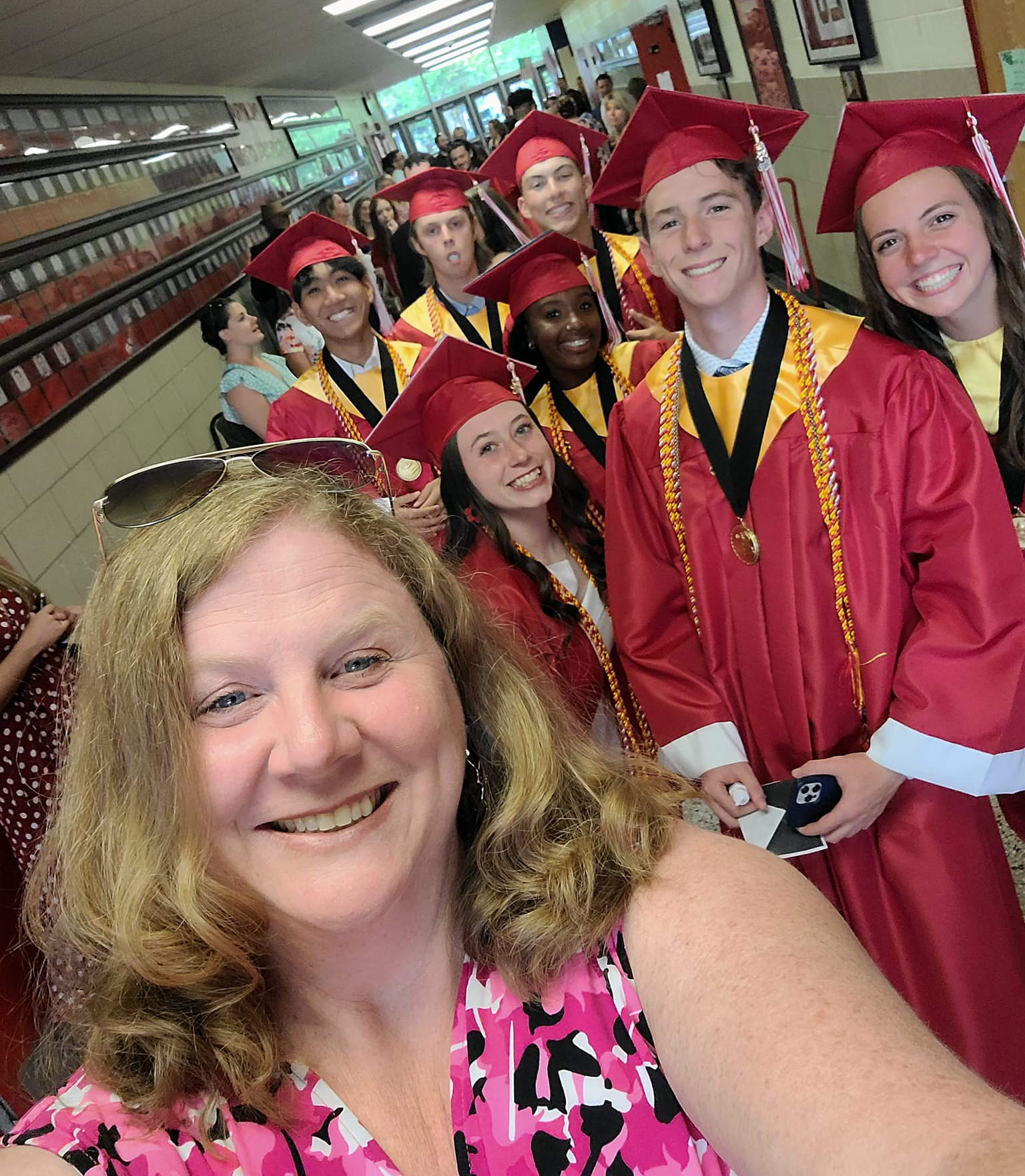 Mrs. Martino in the PHS hall with grads in cap & gown