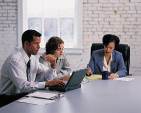 Employees sitting at a table working on a laptop. 