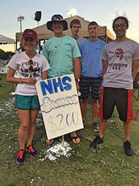 Students standing around a sign that says NHS 