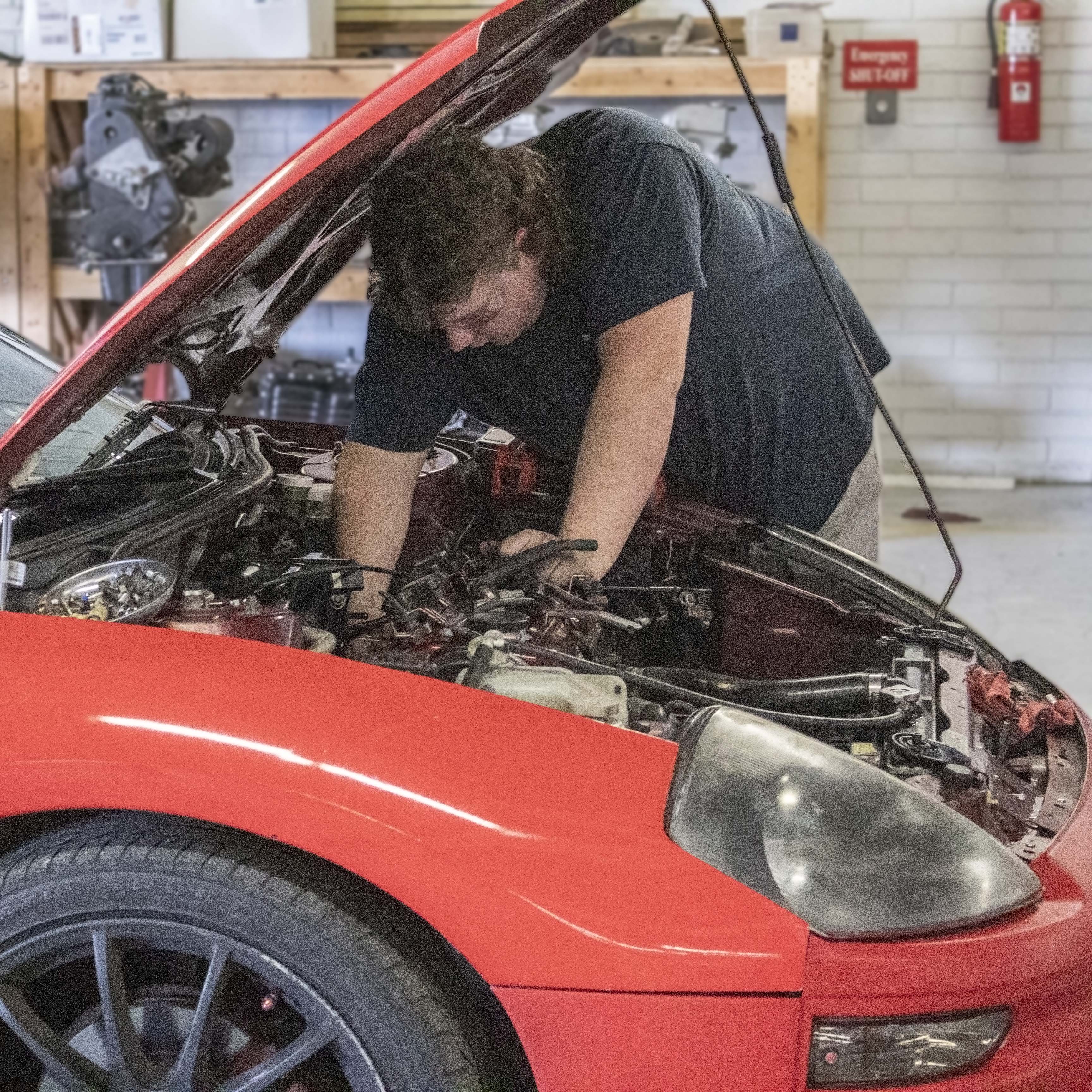 student working under hood of car in the auto shop at CTC